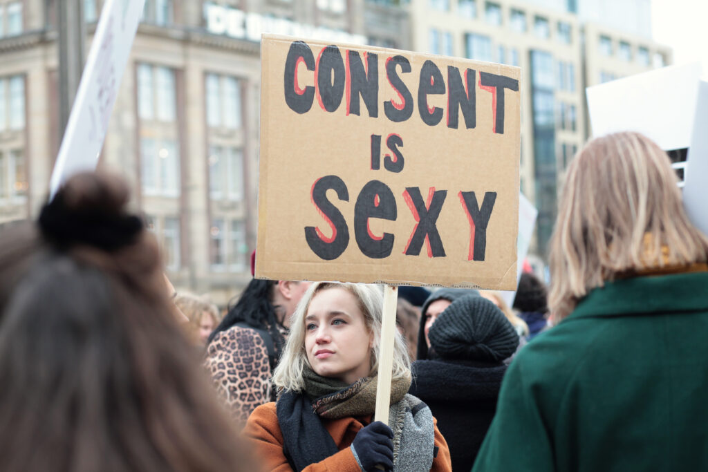 Woman holding a sign saying "Consent is Sexy" which is the cornerstone of the swinger lifestyle and its beliefs.